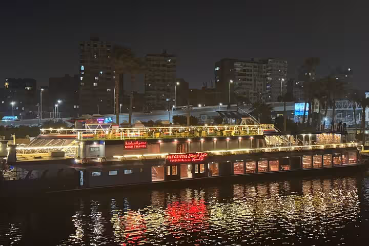 Illuminated Nile River dinner cruise boat in Cairo at night with city skyline reflections, evening tour with hotel pickup
