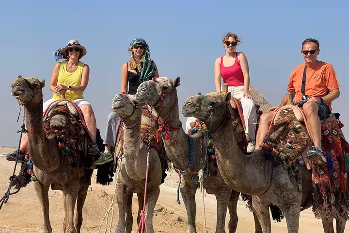 Tourists on camel safari near the Pyramids of Giza, Fly to Cairo tour with optional Tutankhamun mask