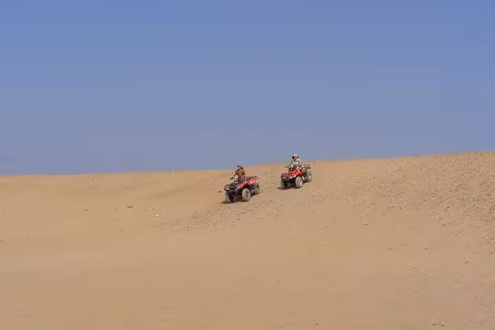 Riders on quad bikes crossing Cairo desert dunes on a thrilling ATV ride, part of Cairo day tour adventure