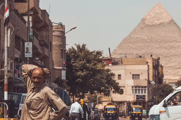 Cairo street scene with Giza Pyramid in the background, part of a private guided pyramids and Sphinx tour with transfers