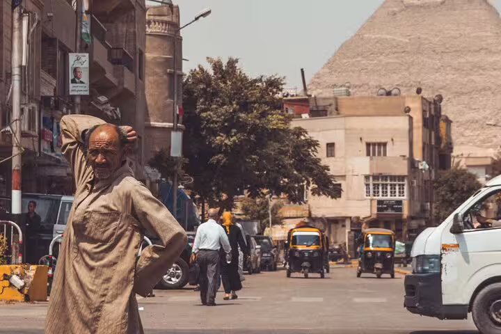 Cairo street scene near the Giza Pyramids with local traffic and tuk-tuks, part of pyramids museum dinner cruise tour