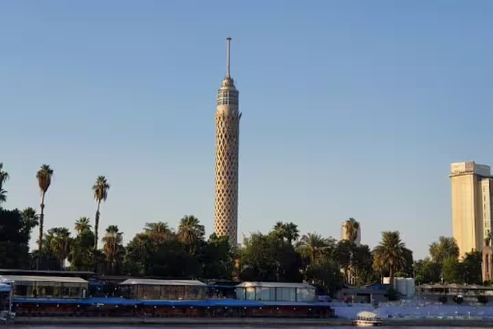 Cairo Tower rising above palm trees at sunset, highlight of El-Muizz Street and dinner experience