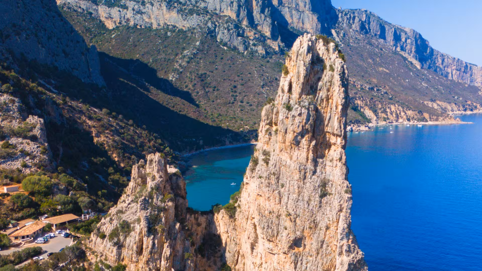 Dramatic rocky cliffs overlooking the turquoise waters of Cala Goloritzè on a sunny day in Sardinia.