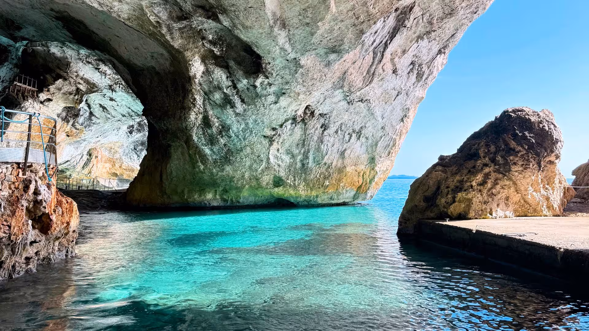 Crystal-clear turquoise waters flow into a large cave entrance along the Gulf of Orosei coast.
