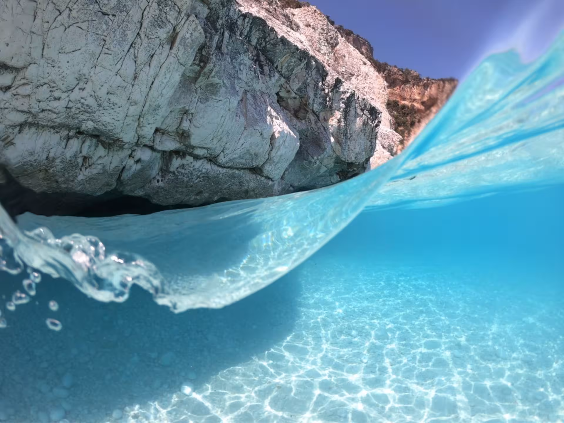 Crystal-clear turquoise water with rocky cliffs in the Gulf of Orosei, perfect for snorkeling adventures.