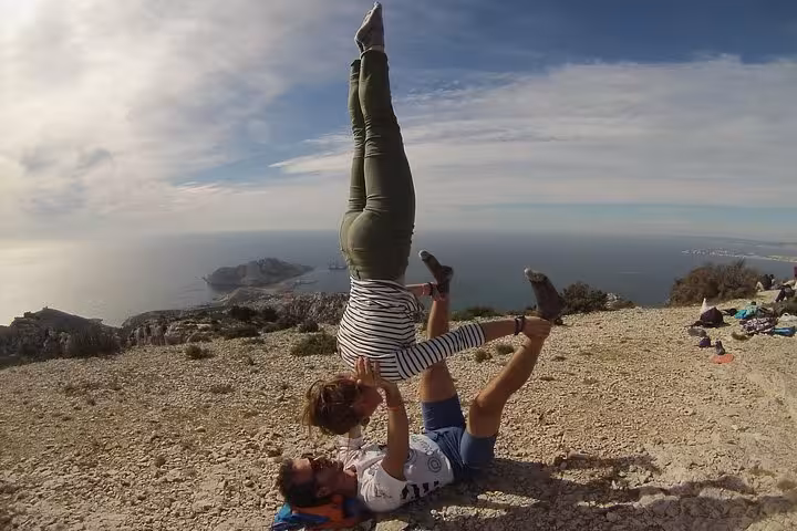 Hikers doing acro yoga on a Calanques viewpoint above Marseille, a fun stop on a 3-day Calanques tour