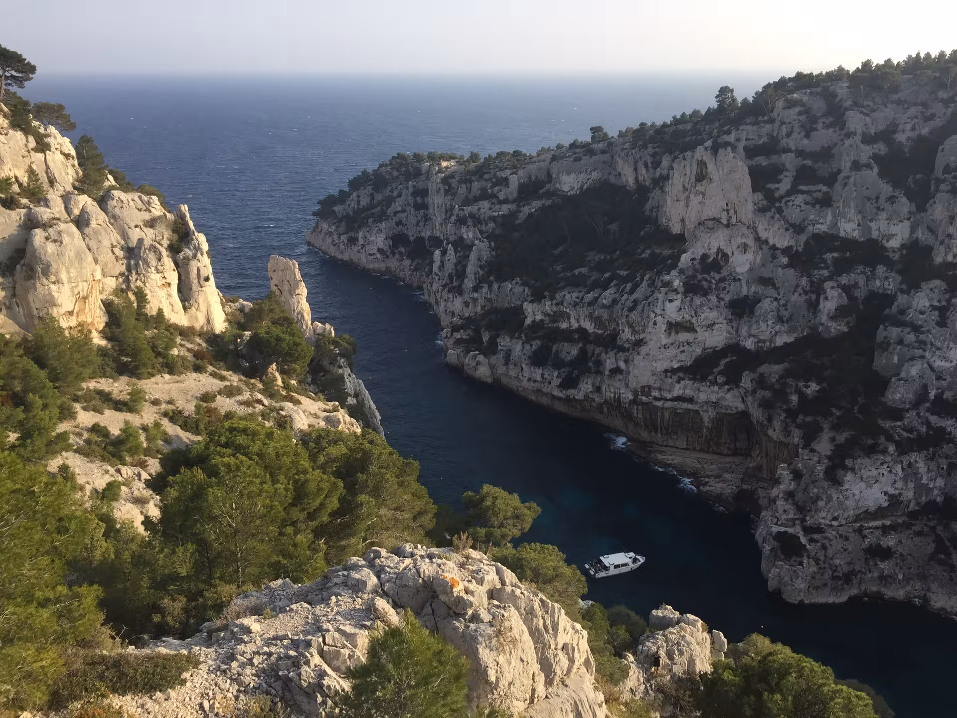 Aerial view of Calanques cliffs and turquoise inlet near Marseille, with boat below on a 3-day Calanques tour