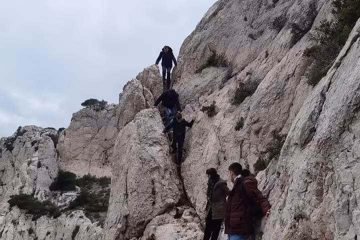 Hikers climbing a narrow limestone ridge in the Calanques, Marseille 3-day guided trekking tour