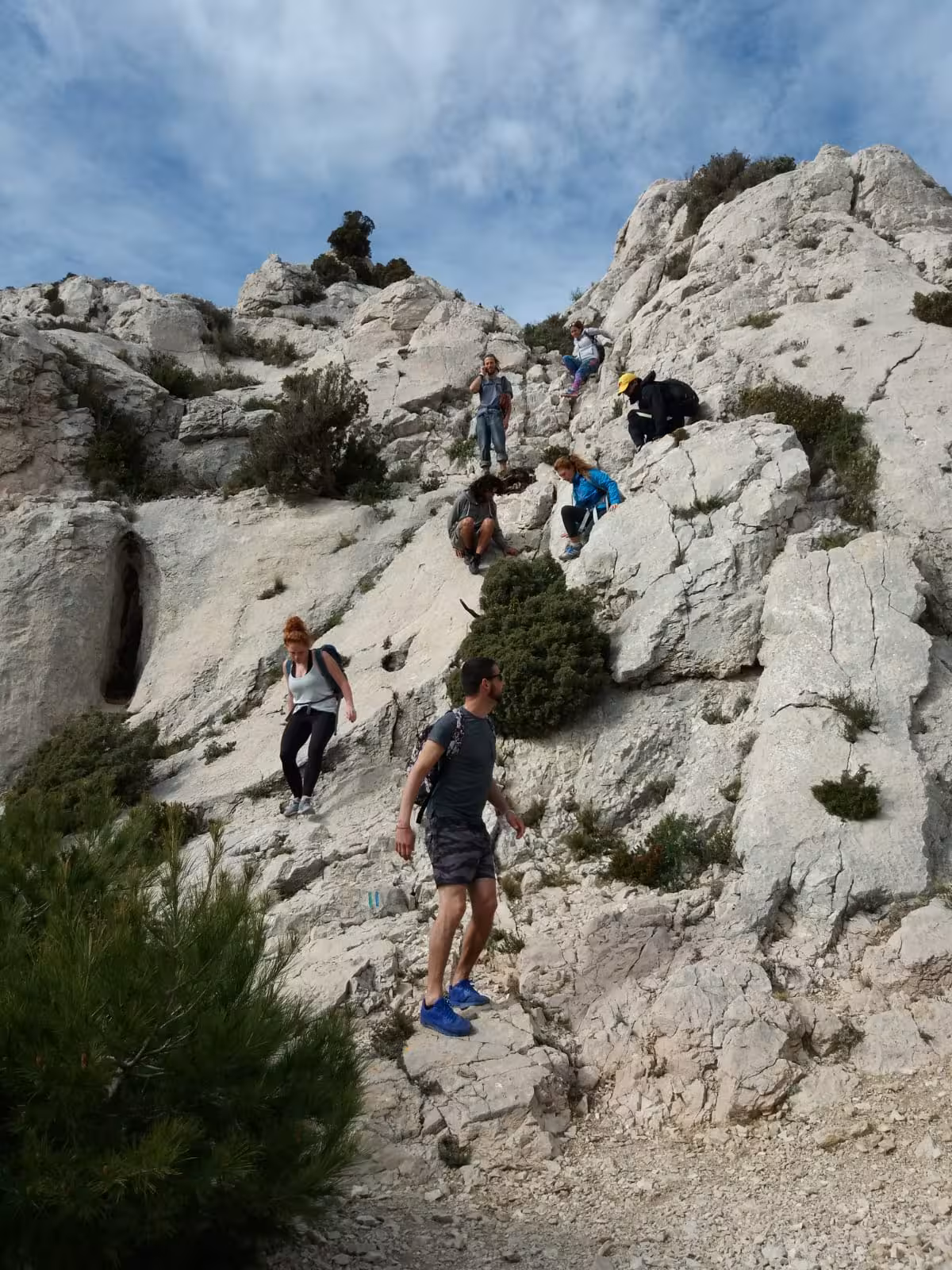 Hikers scrambling down white limestone cliffs in Calanques National Park near Marseille on a 3-day guided trek