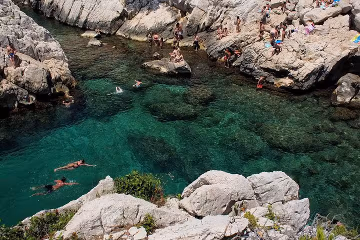 Swimmers in a turquoise Calanques cove on a Marseille hiking tour in Calanques National Park, France