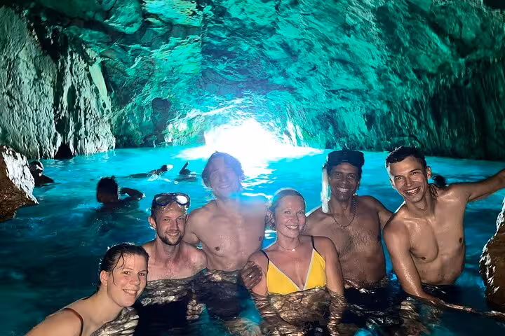Group swimming in a sea cave with glowing blue water on a Calanques National Park hike from Marseille