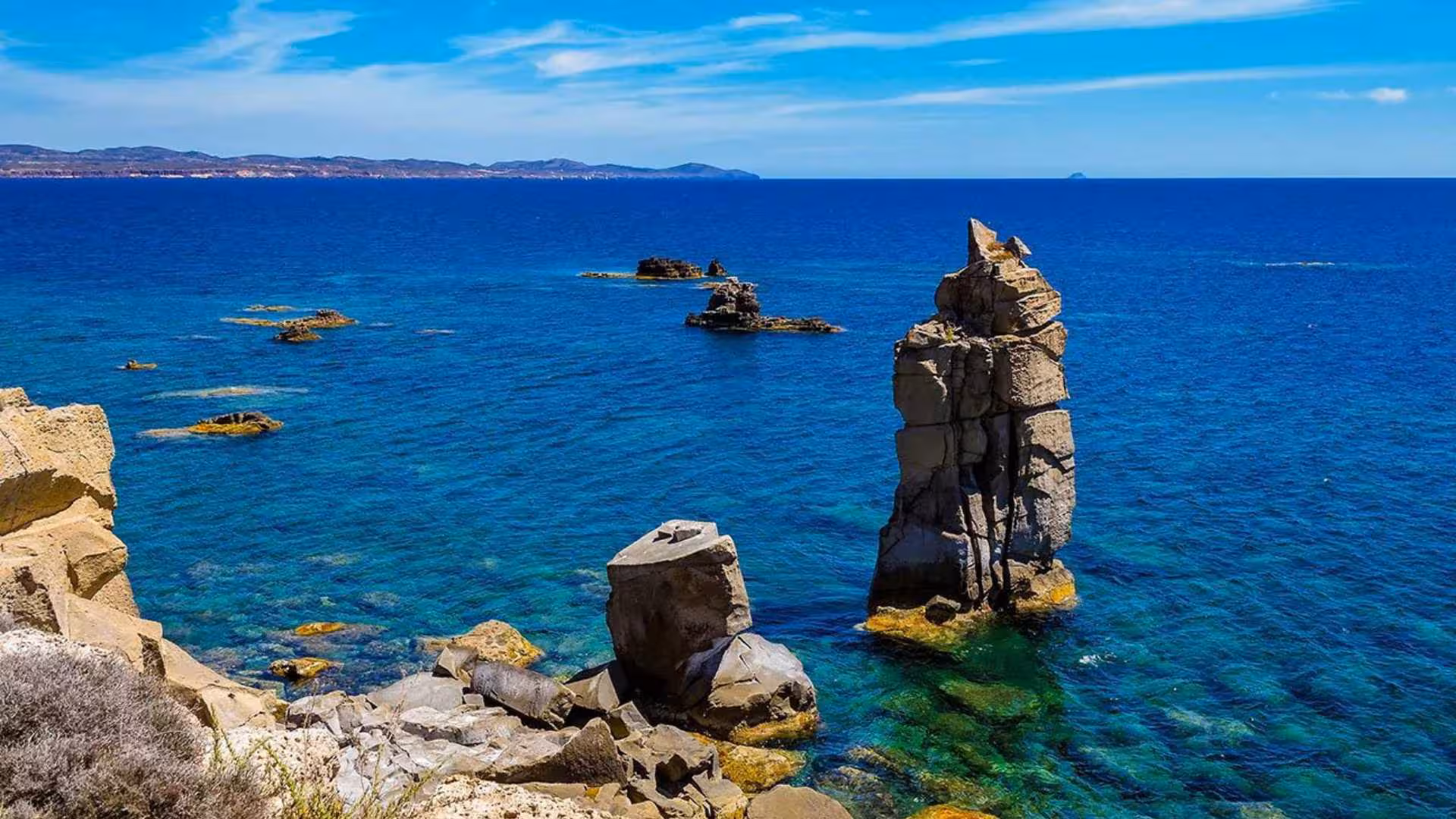 Stunning rock formations rise from the clear blue sea in Calasetta, a prime spot for RIB hire excursions.