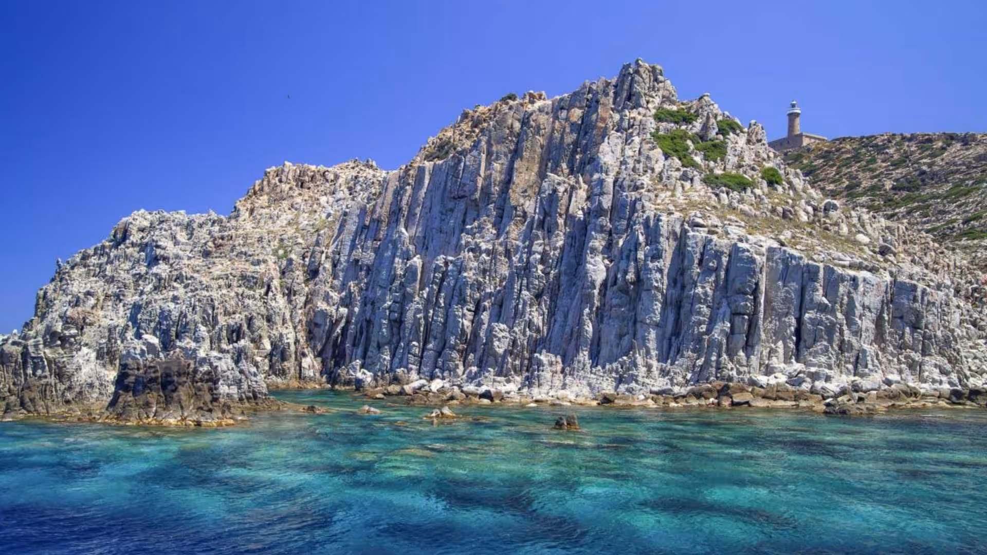Dramatic rocky cliffs and crystal-clear waters in Calasetta, showcasing ideal conditions for RIB hire tours.