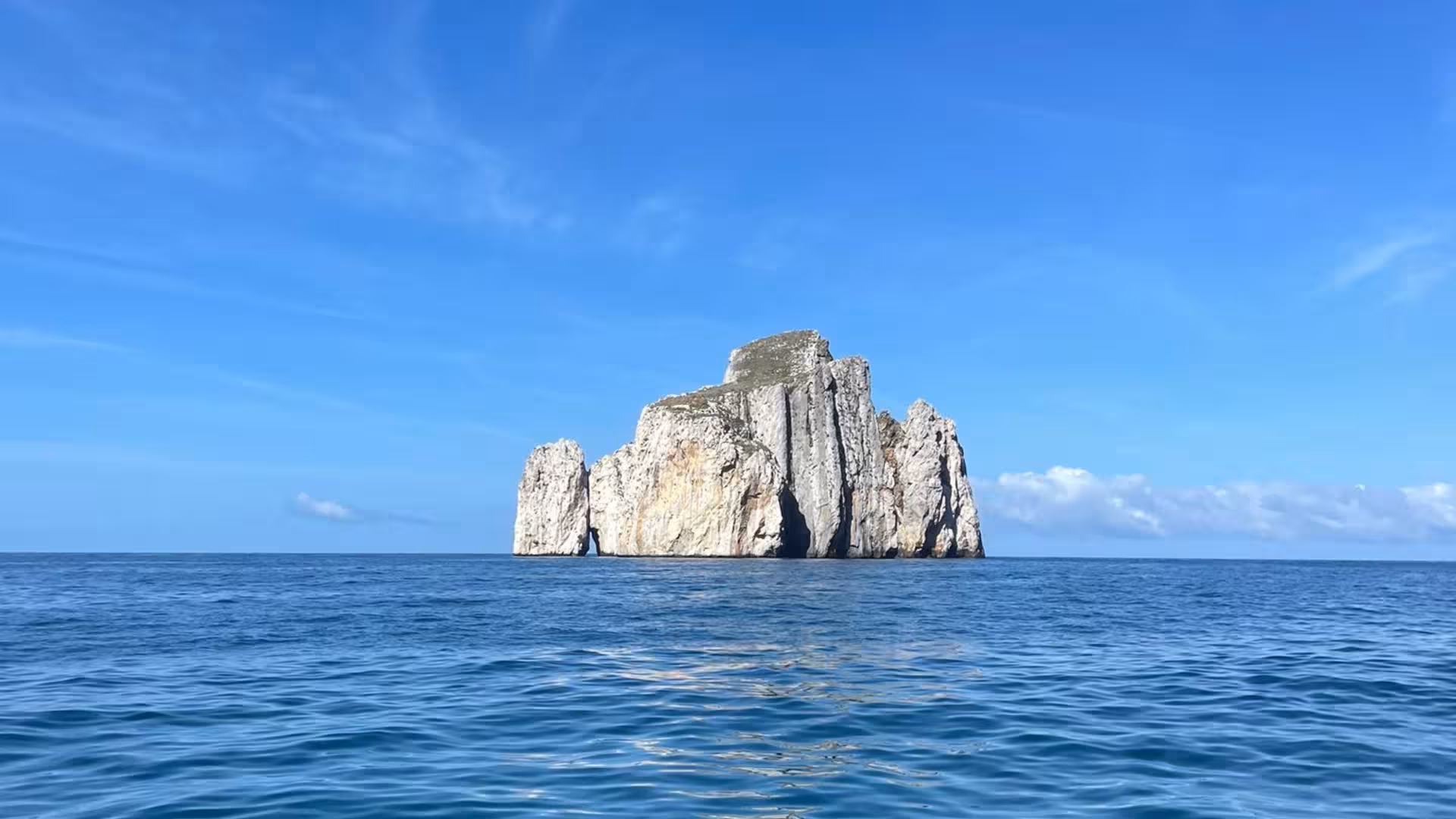 Majestic rock formation rising from the clear blue sea near Calasetta, perfect for RIB hire adventures.