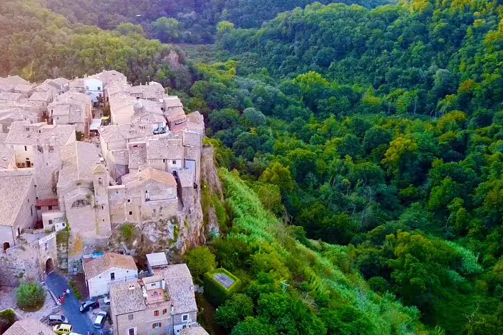 Drone view of Calcata medieval village perched on a cliff above lush forest on Rome, Calcata, Bomarzo VIP private tour