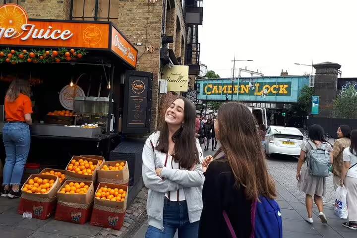 Visitors enjoy a vibrant day at Camden Lock with fresh orange juice stands, capturing the essence of London's lively markets.