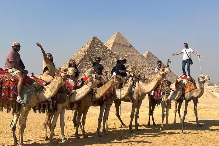 Travelers on camel ride in front of the Giza Pyramids, part of private adventure tour with ATV and lunch