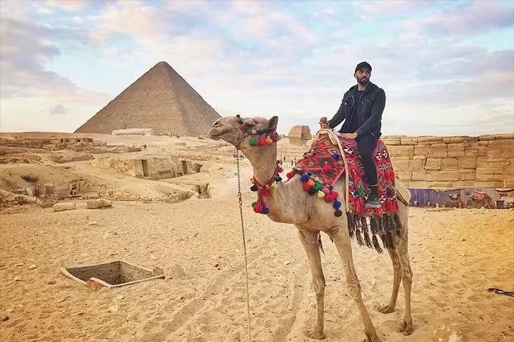 Camel ride at Giza Pyramids with colorful saddle, ideal Egypt day tour by camel near Cairo desert plateau