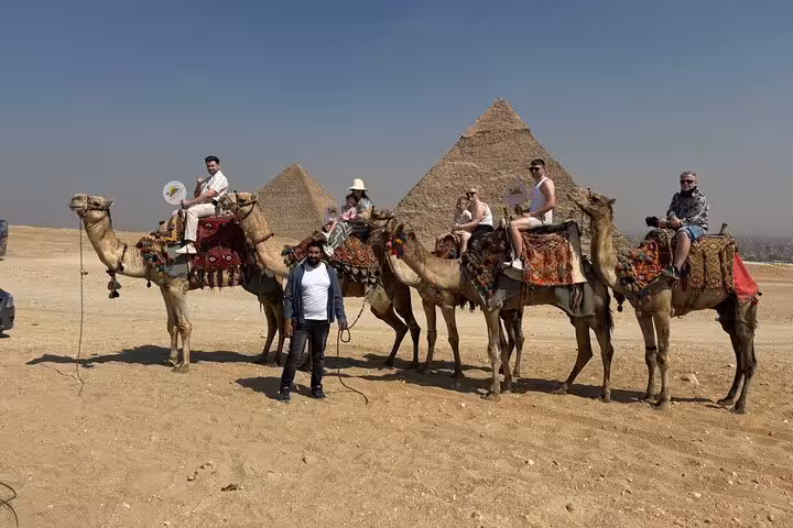 Camel ride with travelers at Giza Pyramids on private tour, desert views near the Sphinx and Grand Egyptian Museum