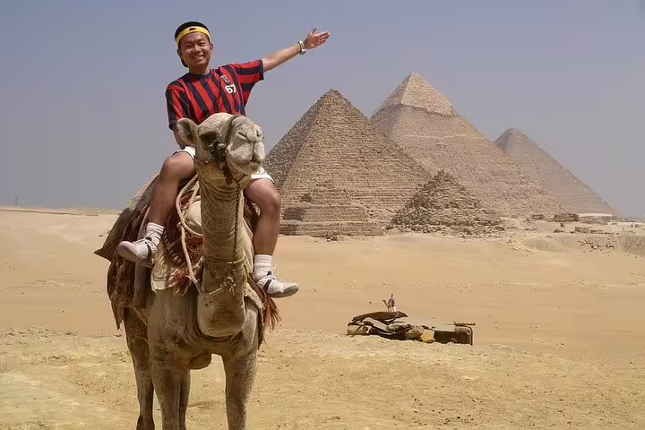 Traveler on camel with Giza Pyramids backdrop, ideal for sunrise or sunset camel ride tour in Egypt