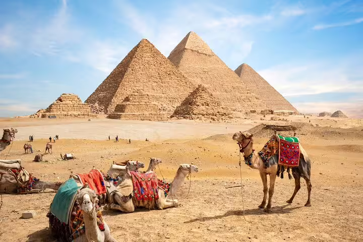 Camel ride scene at the Great Pyramids of Giza under blue sky, Egypt half-day pyramids tour experience