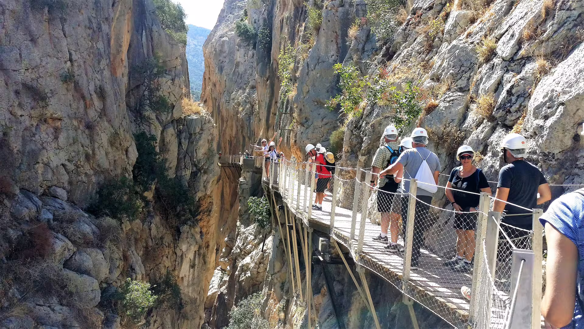Caminito del Rey group walking tour crossing suspended boardwalk above the gorge in El Chorro, Malaga