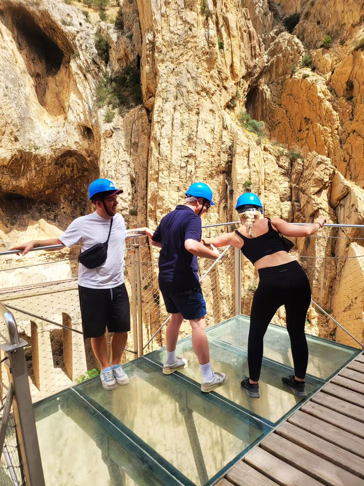 Visitors in blue helmets on the glass viewpoint at Caminito del Rey gorge on a private tour from Marbella