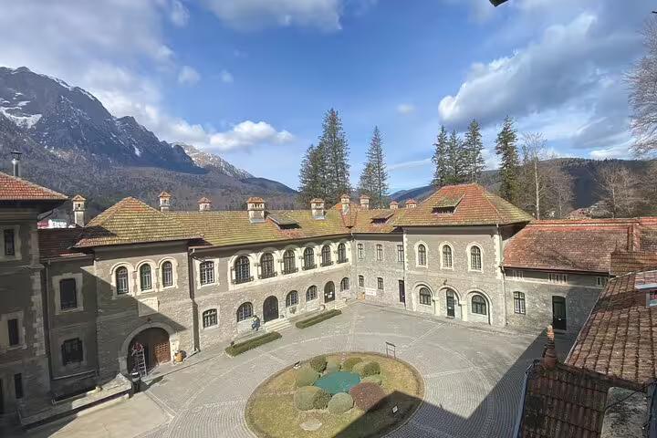 Cantacuzino Castle courtyard with arched stone facade and snow-capped Carpathian mountains in background