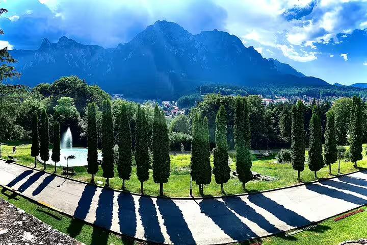 Formal garden with cypress trees and fountain, Cantacuzino Castle grounds with Bucegi Mountains backdrop