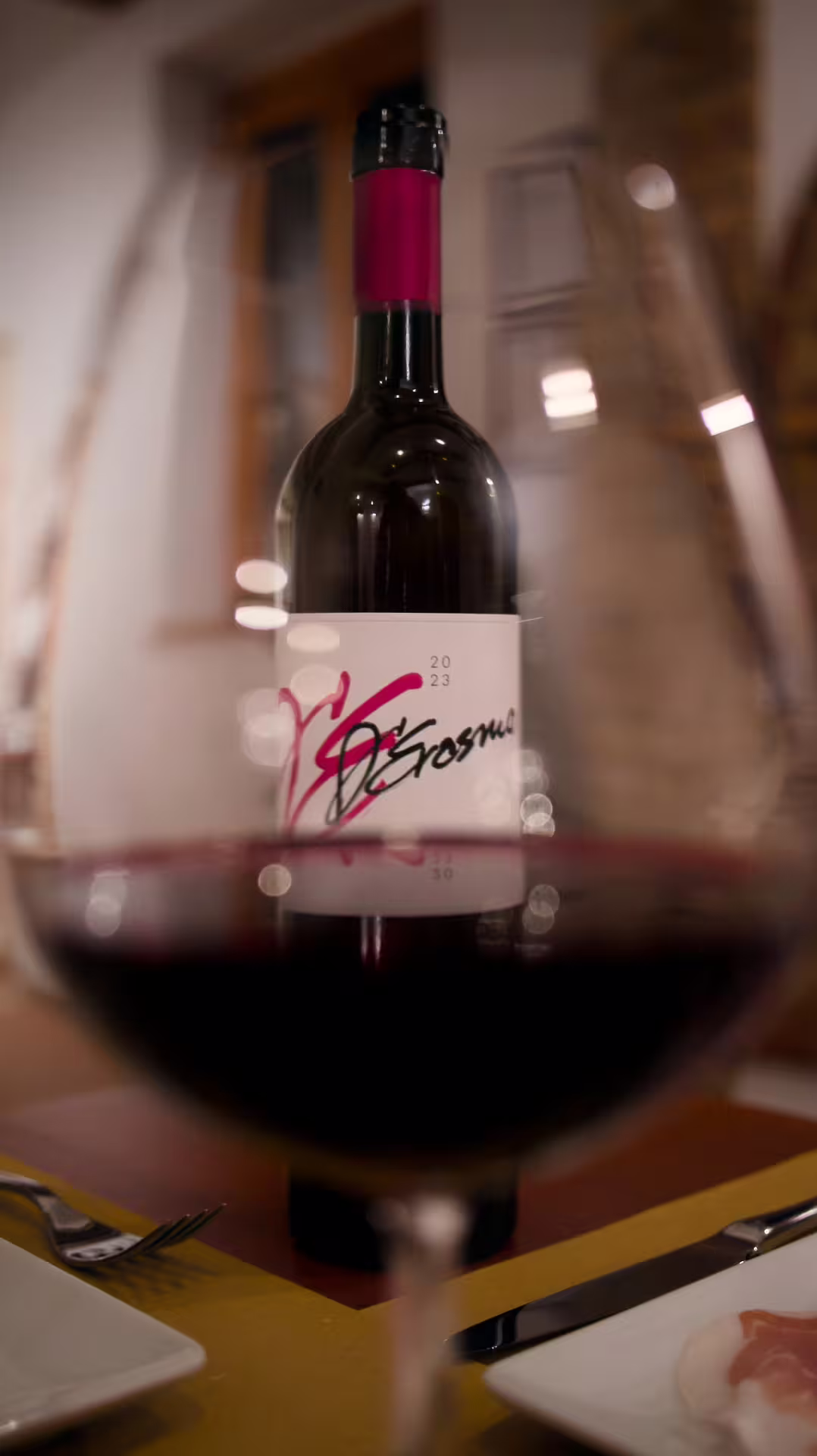 Glass of red wine in foreground with Cantina D’Erasmo bottle, Marche winery tasting experience in Italy