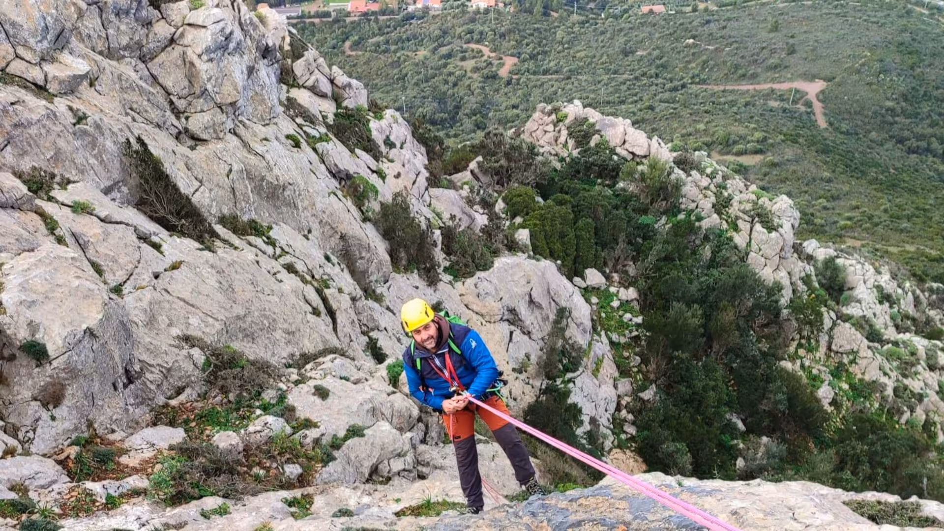 Canyoning enthusiast abseiling down rocky cliffs at Monte San Giovanni with lush landscape views.
