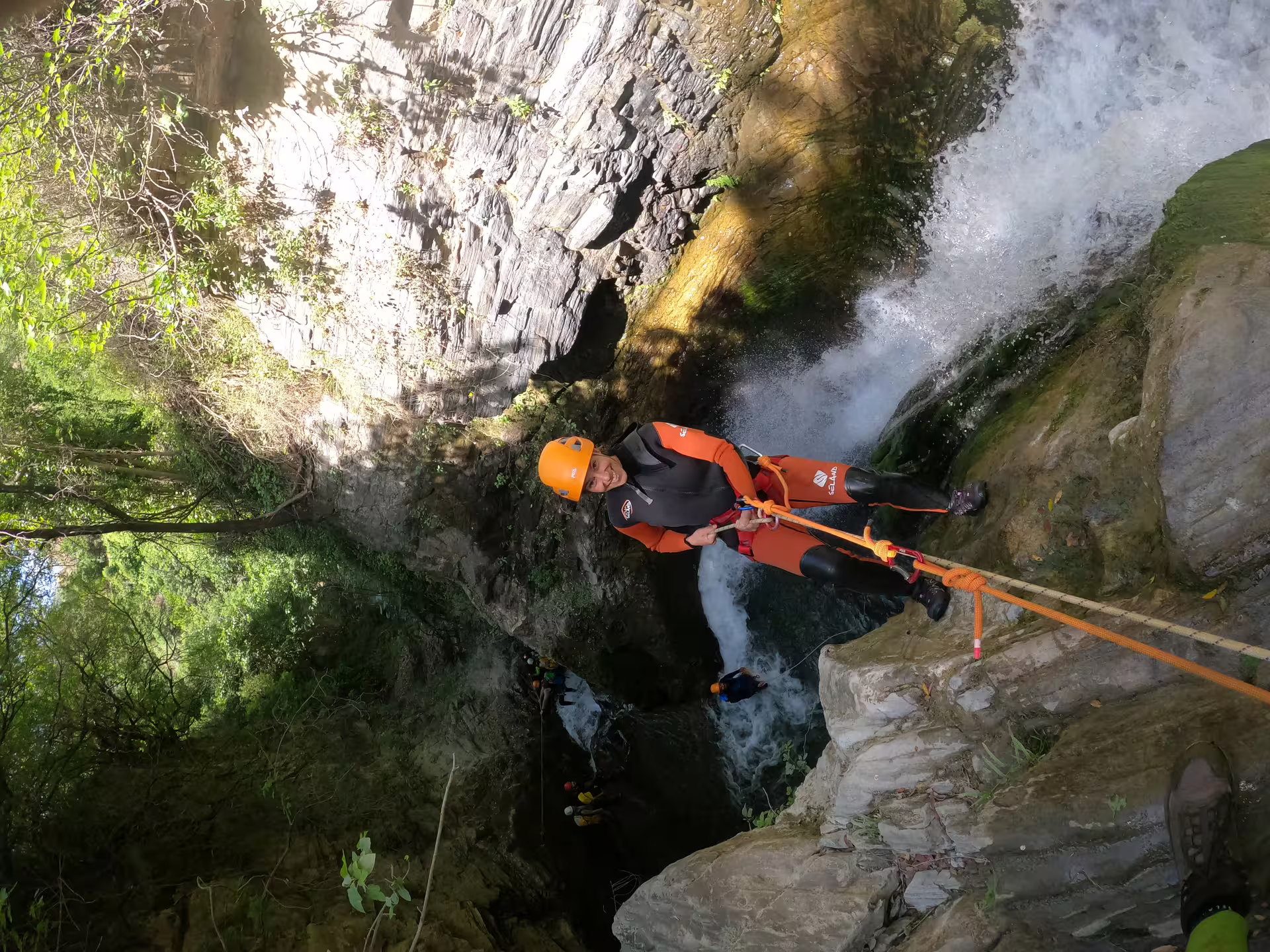 Adventurer abseiling down a waterfall during a canyoning tour at Sima del Diablo, surrounded by lush greenery near Estepona.