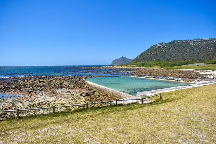 Scenic view of a tidal pool and rocky coastline at Cape of Good Hope under a clear blue sky, perfect for a private tour.