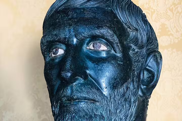 Close-up of ancient bronze bearded head sculpture displayed inside Rome’s Capitoline Museums on a guided tour