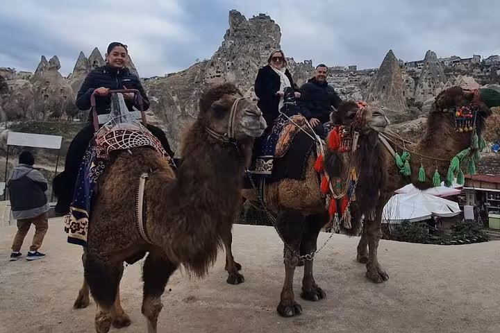 Travelers on camel ride in Cappadocia with fairy chimneys, part of a private day tour with guide and vehicle