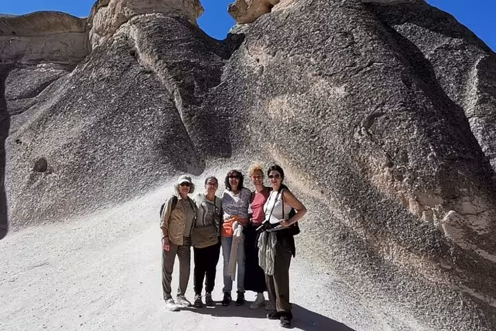 Travelers pose by Cappadocia fairy chimney rocks on a private tour with English guide and luxury vehicle