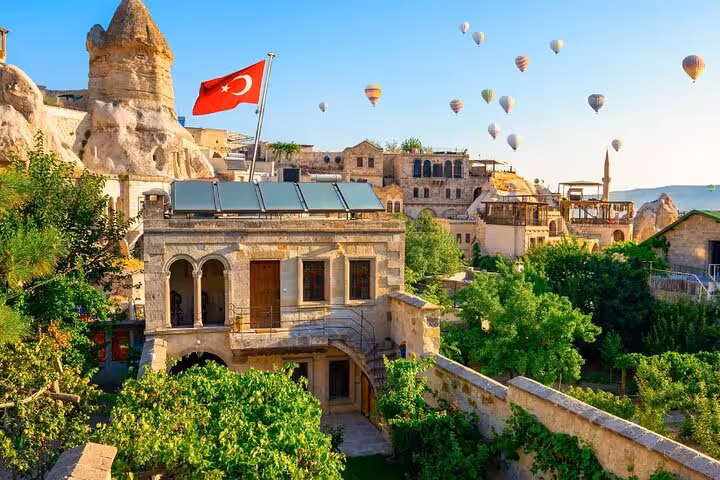 Göreme boutique cave hotel view with Turkish flag and balloons, Cappadocia private guided tour with balloon option