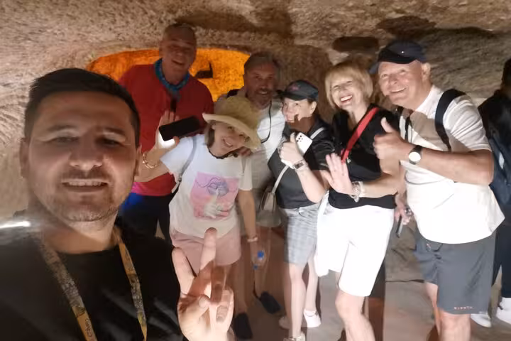 Travelers inside Cappadocia cave on Green Full-Day Tour, group photo in rock-cut passage with guide