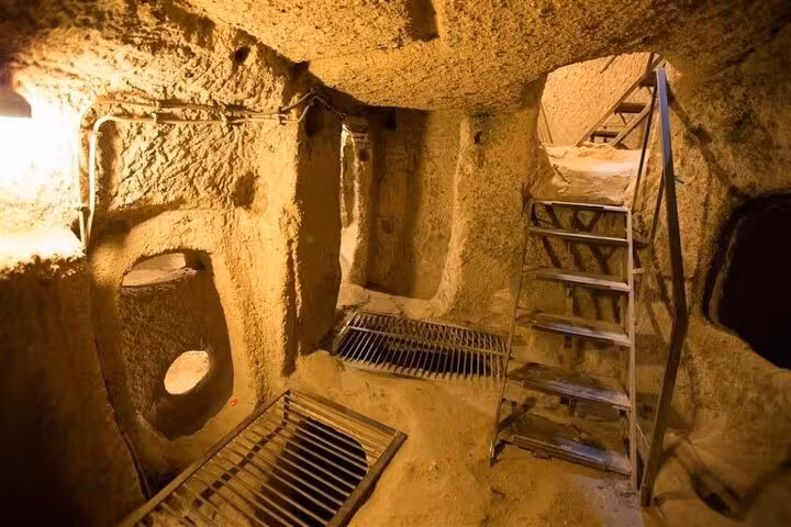 Cappadocia Green Tour stop at an underground city chamber with carved tunnels, ladders and stone walls