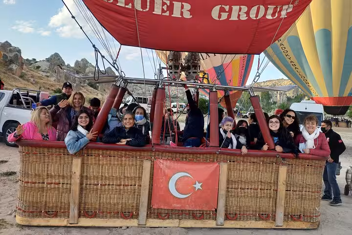 Cappadocia hot air balloon basket group photo on Spanish 2-day tour with internal flights, Turkey flag visible