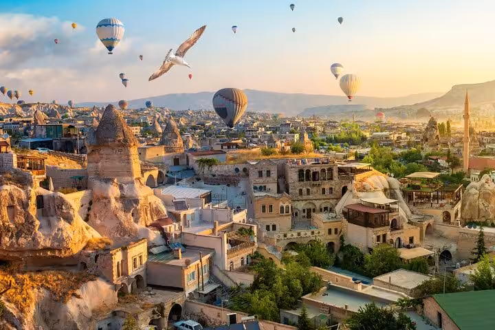 Sunrise hot air balloons over Cappadocia cave hotels, ideal for private guided tour with balloon option