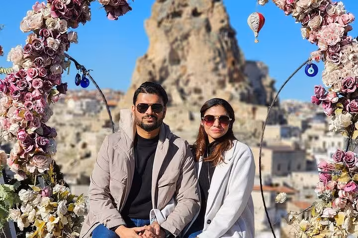 Couple photo at Uchisar Castle viewpoint with hot air balloon on Cappadocia private guided tour