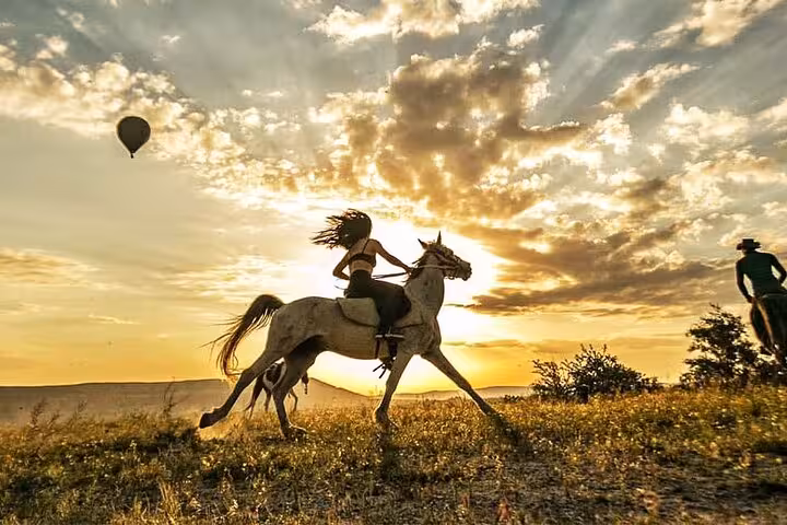 Rider gallops at sunset in Cappadocia with hot air balloon views on a 2-hour horseback riding tour