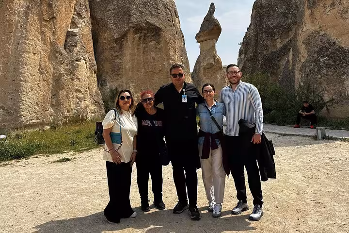 Small group Cappadocia tour group posing by fairy chimney rock formations on guided day trip excursion