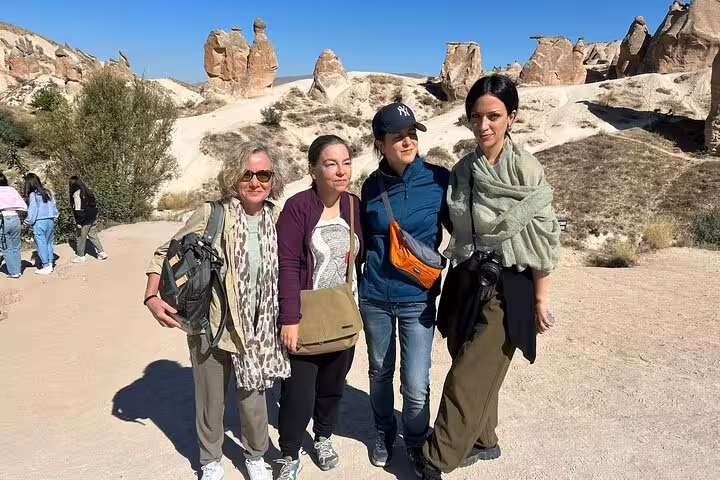 Small group Cappadocia tour guests posing by fairy chimneys in Pasabag Valley during guided day trip