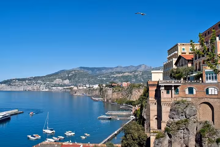 Stunning view of Capri's coastline with cliffs, luxury villas, and boats, ideal for a half-day Blue Grotto boat tour.