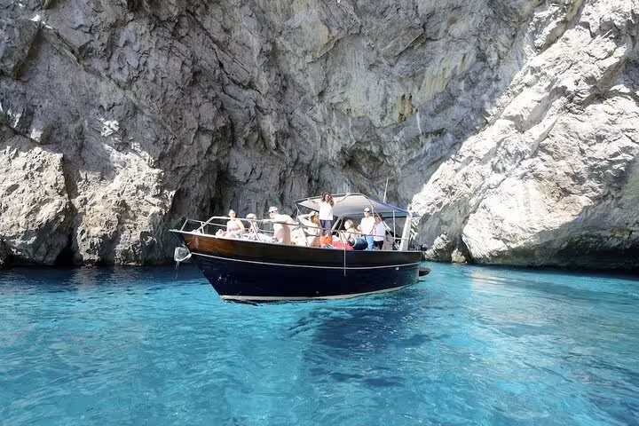 Tourists enjoy a scenic Capri boat tour near the Blue Grotto, surrounded by striking cliffs and crystal-clear waters.