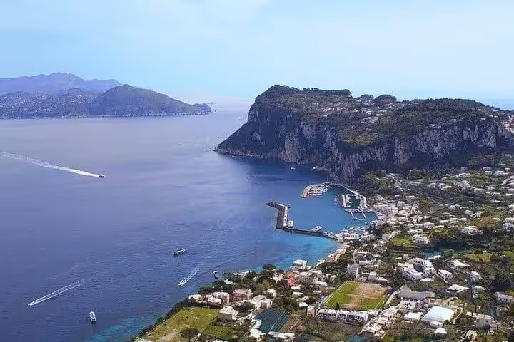 Aerial view of Capri's dramatic coastline with lush greenery and azure waters, perfect for scenic exploration.