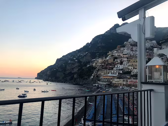 Sunset over Positano coastline from a terrace, boats on the sea on the From Dusk Till Night experience
