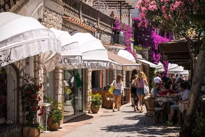 Charming street in Capri with vibrant flowers, boutique shops, and al fresco dining experiences.